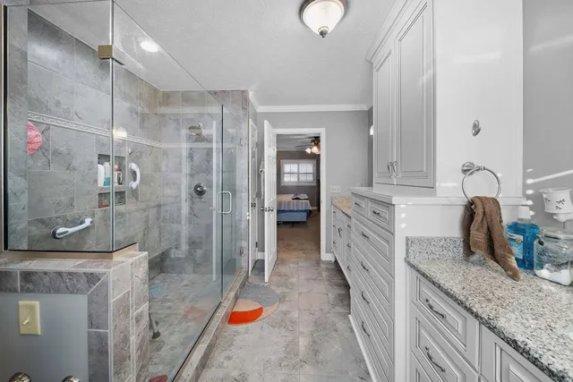 a bathroom with a granite countertop sink a mirror and shower