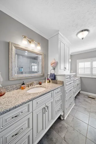 a bathroom with a granite countertop double vanity sink and mirror