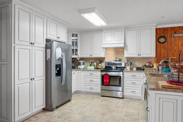 a kitchen with stainless steel appliances granite countertop a refrigerator sink and stove