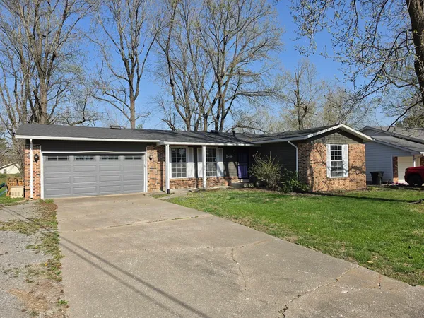 a front view of a house with a garden and trees