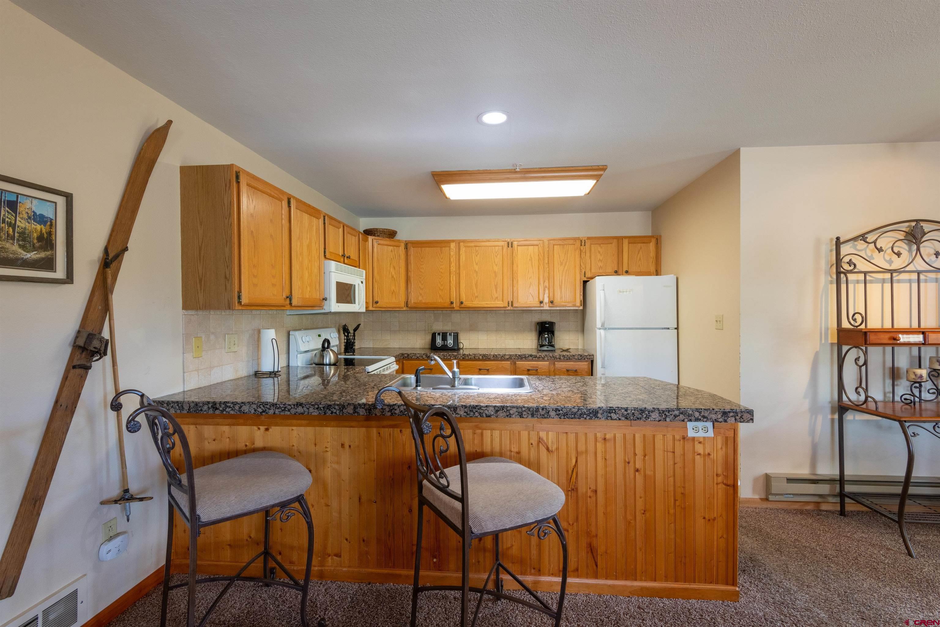 33 Castle Road, Unit 3 Crested Butte, CO 81225 - Photo 6 of 34 a kitchen with granite countertop cabinets and chair