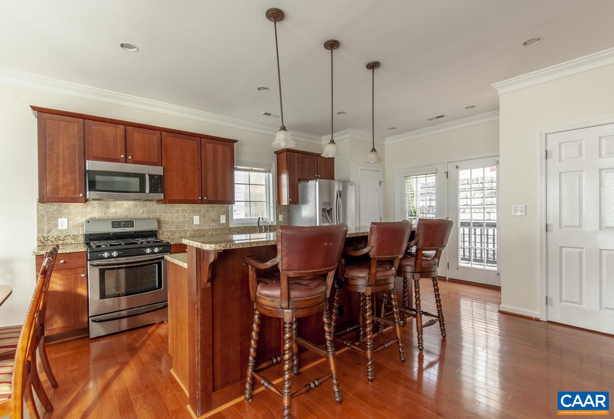 345 Quarry Road Charlottesville, VA 22902 - Photo 8 of 32 a kitchen with stainless steel appliances granite countertop a stove top oven a sink a dining table and chairs with wooden floor