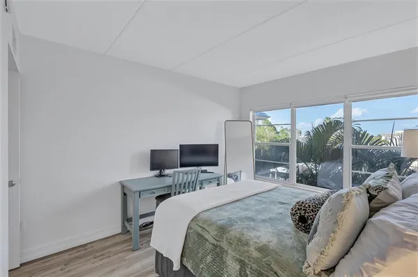 a bedroom with a bed a large window and flat screen tv