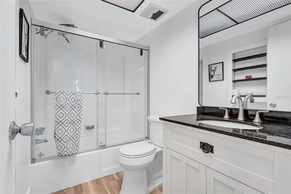 a bathroom with a granite countertop sink a toilet and shower