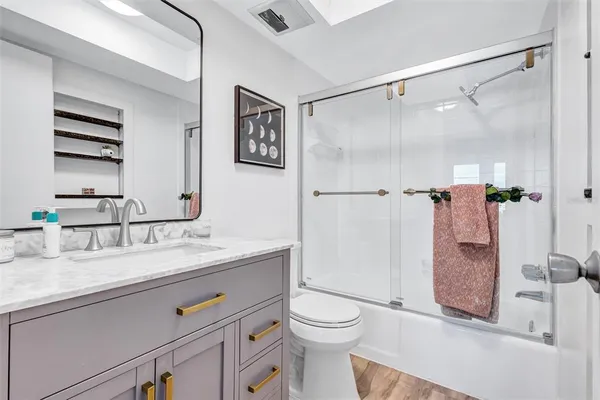 a bathroom with a granite countertop sink mirror vanity and toilet