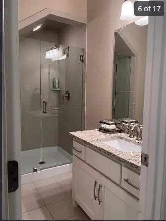 a bathroom with a granite countertop sink a mirror and shower