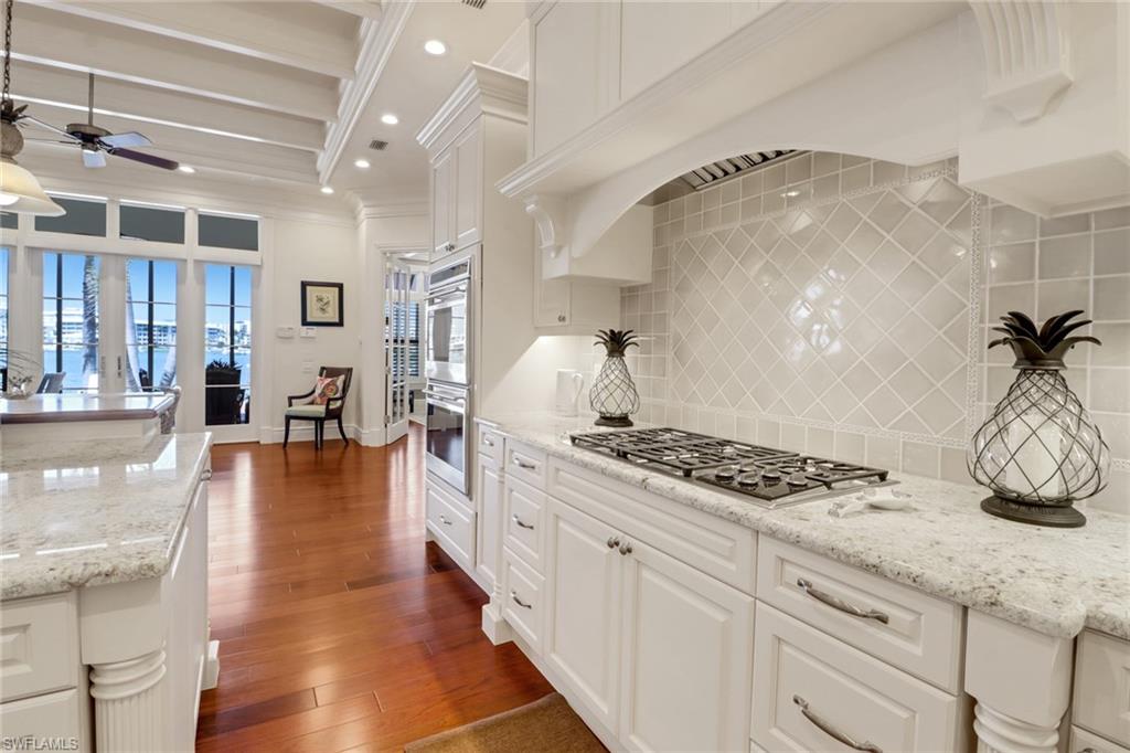 2621 Windward Way Naples, FL 34103 - Photo 11 of 37 a kitchen with granite countertop a stove oven and white cabinets with wooden floor