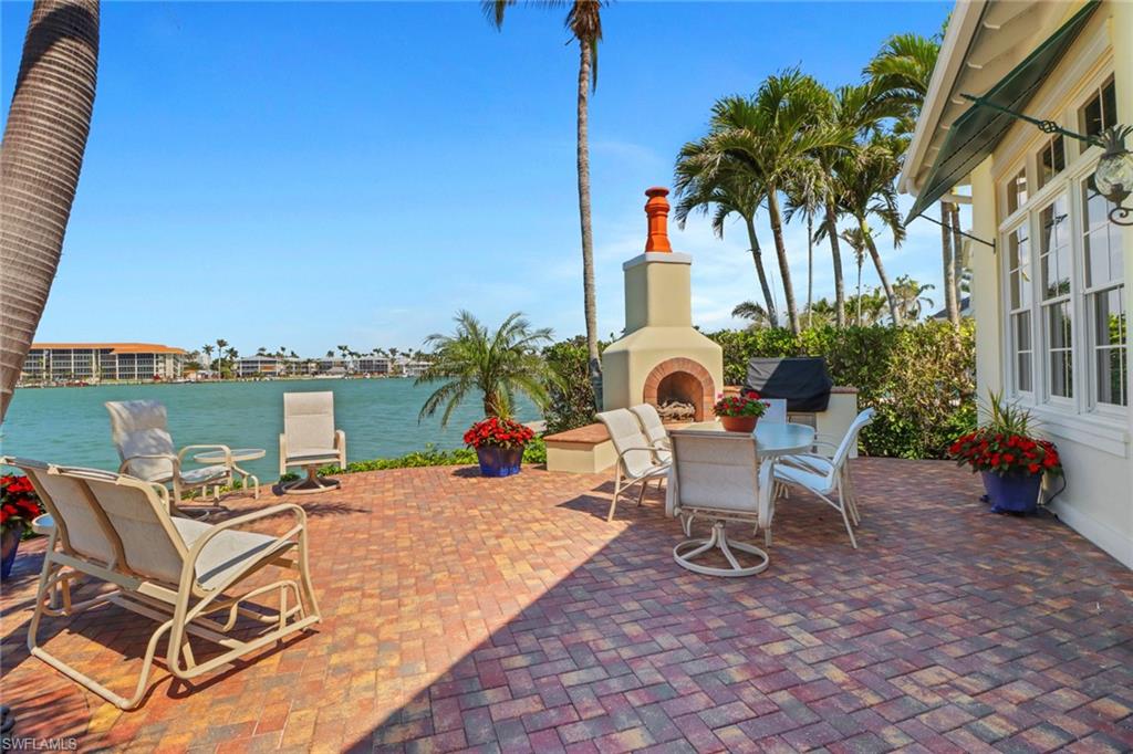 2621 Windward Way Naples, FL 34103 - Photo 35 of 37 a view of a patio with table and chairs potted plants and palm tree