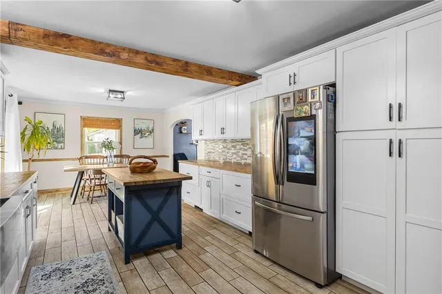 a kitchen with stainless steel appliances a refrigerator a stove a sink dishwasher and white cabinets with wooden floor