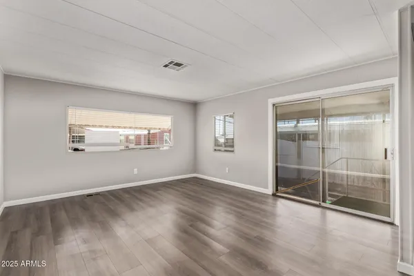 an empty room with wooden floor and windows