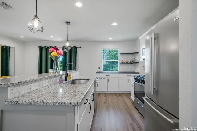 a kitchen with granite countertop stainless steel appliances a sink stove and cabinets