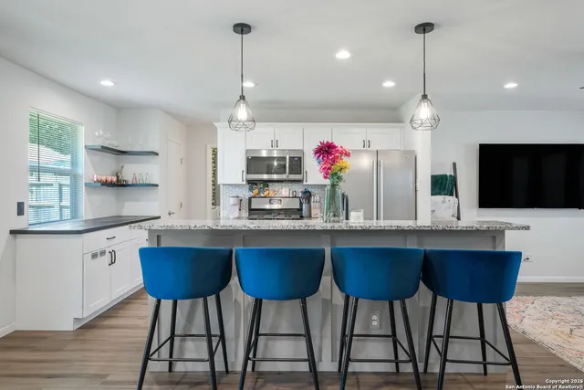 a kitchen with granite countertop a dining table chairs sink and white cabinets