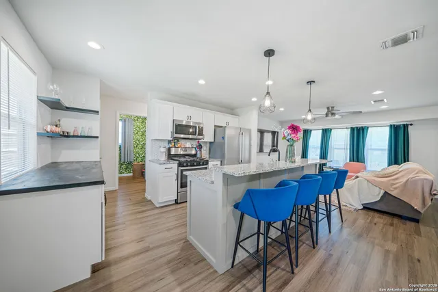 a kitchen with stainless steel appliances kitchen island granite countertop a table chairs and a refrigerator