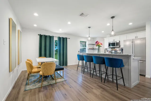 a kitchen with stainless steel appliances granite countertop a dining table chairs refrigerator sink and cabinets