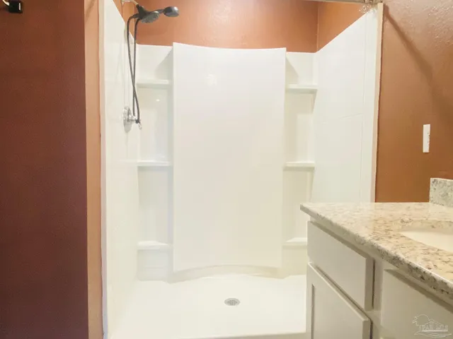 a bathroom with a granite countertop shower and a sink
