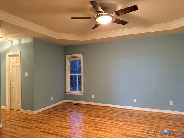 an empty room with wooden floor closet and windows