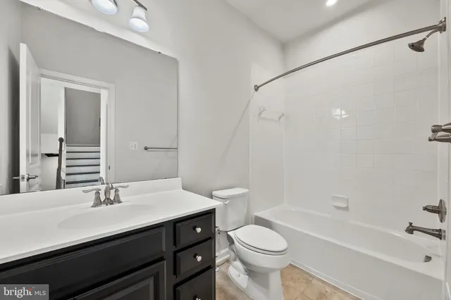 a bathroom with a bathtub shower sink vanity mirror and toilet