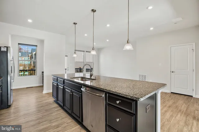 a kitchen with stainless steel appliances granite countertop a sink a stove and a wooden floors