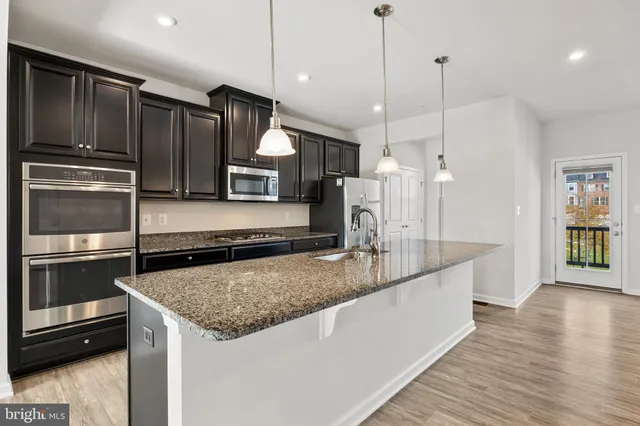 a kitchen with kitchen island a counter space a sink appliances and cabinets