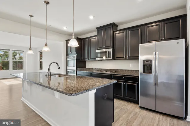 a kitchen with stainless steel appliances granite countertop a sink a stove a refrigerator and island