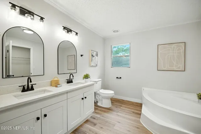 a spacious bathroom with a double vanity sink mirror and bathtub