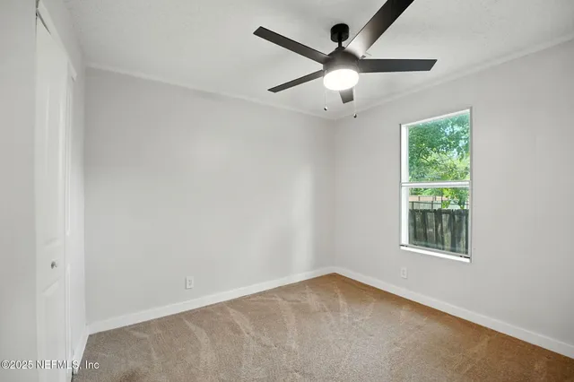 an empty room with a window and a ceiling fan
