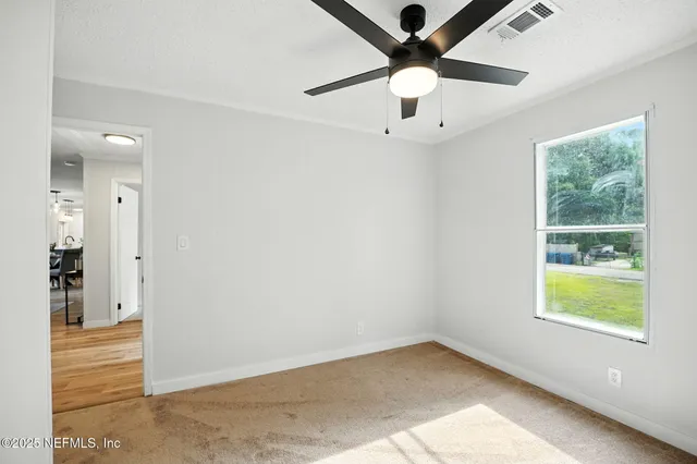 an empty room with windows and fan