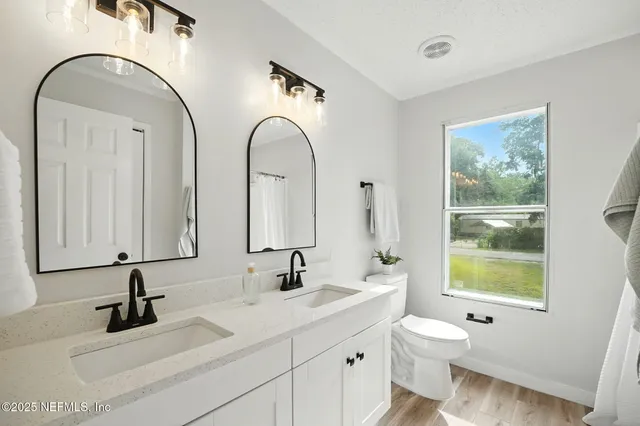 a bathroom with a double vanity sink mirror and toilet