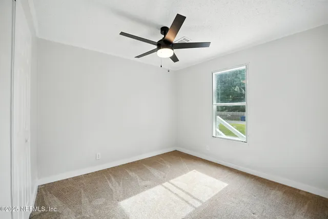 an empty room with ceiling fan and window