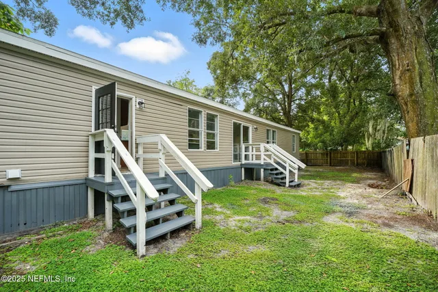 a view of a house with backyard and trees