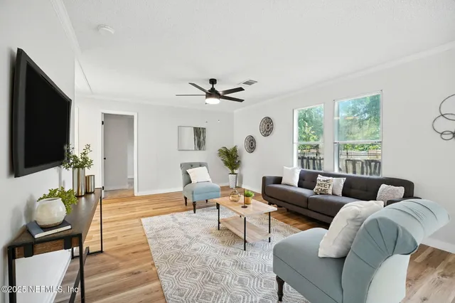 a living room with furniture a flat screen tv and a large window