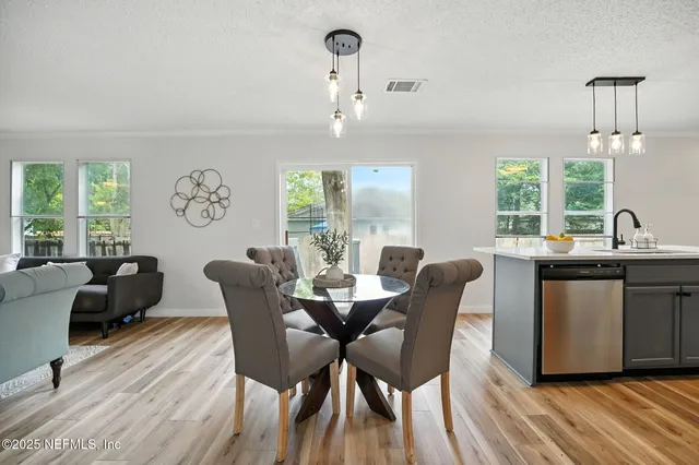a dining room with wooden floor a chandelier a glass table and chairs