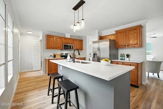 a kitchen with stainless steel appliances granite countertop a table chairs sink refrigerator and cabinets