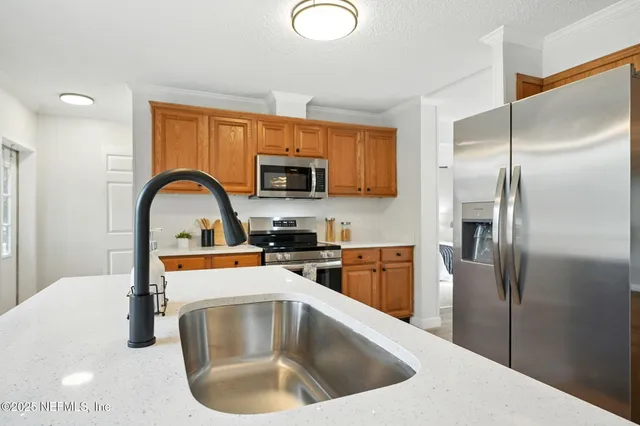 a kitchen with stainless steel appliances granite countertop a sink a refrigerator and a microwave