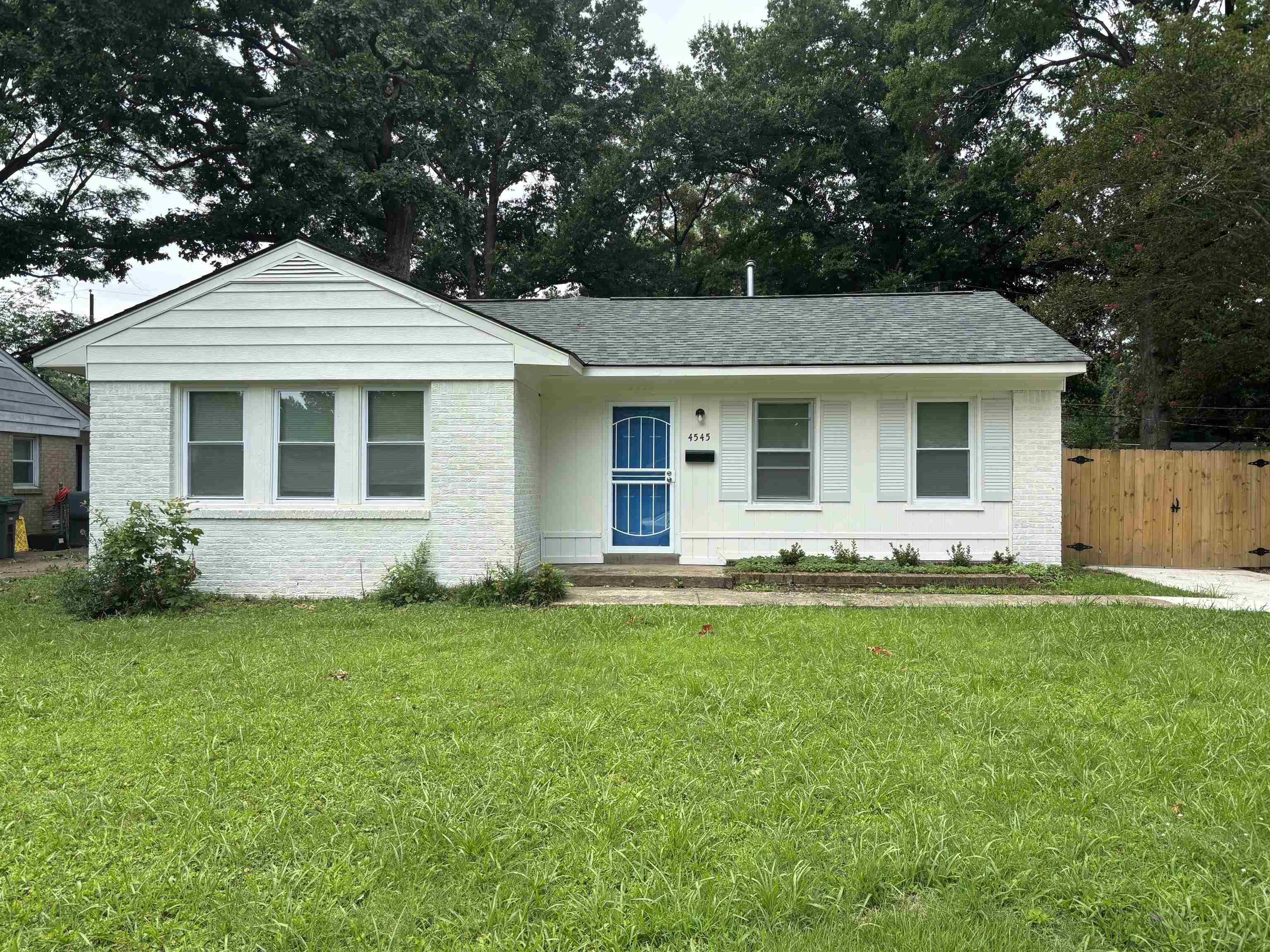 White brick exterior featuring a contrasting blue entry door and a coordinating white storm door