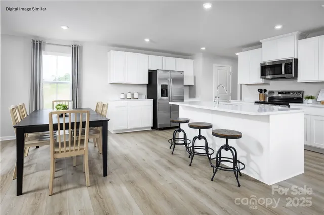 a kitchen with stainless steel appliances kitchen island granite countertop a table chairs and a refrigerator
