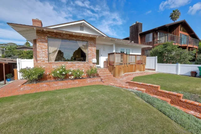 a front view of a house with a yard and potted plants
