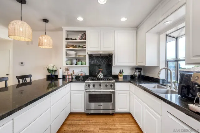 a kitchen with stainless steel appliances granite countertop a stove a sink and a wooden floors