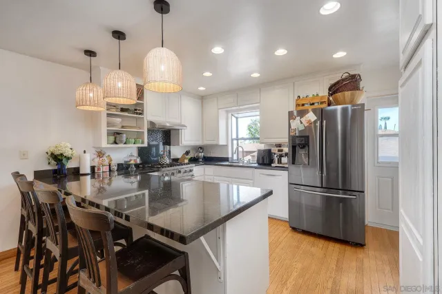 a kitchen with stainless steel appliances granite countertop a refrigerator a sink a stove and a refrigerator