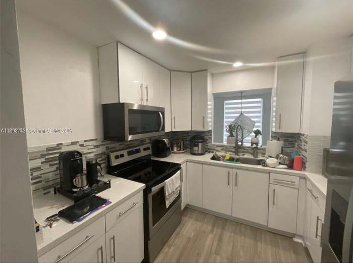 12100 Southwest 271st Street, Unit 12100 Homestead, FL 33032 - Photo 6 of 24 a kitchen with a sink stove and cabinets