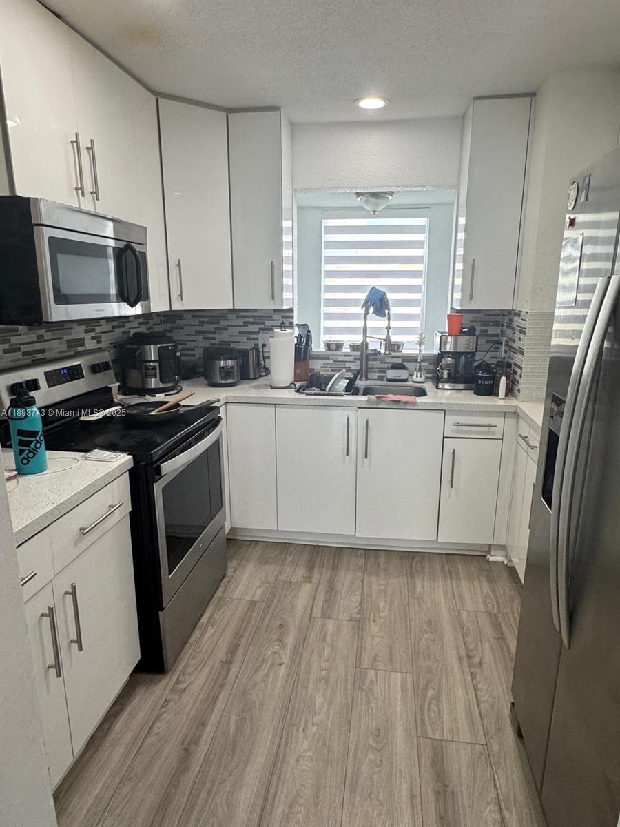 12100 Southwest 271st Street, Unit 12100 Homestead, FL 33032 - Photo 7 of 24 a kitchen with granite countertop a sink stove and refrigerator