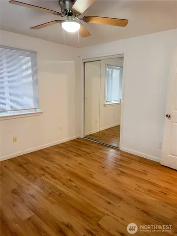 an empty room with wooden floor fan and windows