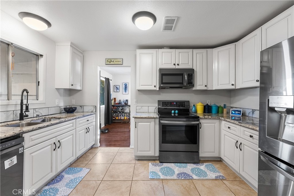 13336 Clement Edwards, CA 93523 - Photo 17 of 56 a kitchen with stainless steel appliances granite countertop a stove top oven a sink dishwasher and a refrigerator with wooden cabinets
