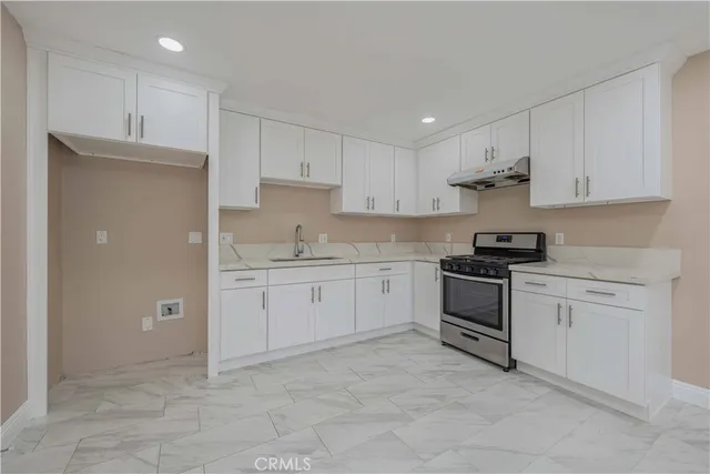 a kitchen with granite countertop a stove sink and cabinets