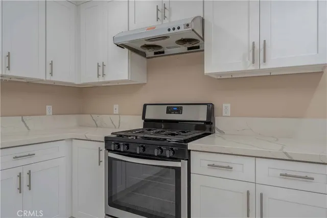 a kitchen with granite countertop white cabinets and a stove top oven