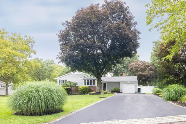 a front view of a house with a garden and trees