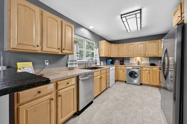 a kitchen with stainless steel appliances granite countertop a stove a sink and white cabinets