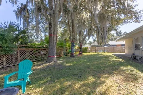 a backyard of a house with table and chairs a fire pit and a large tree