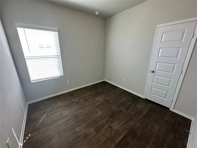 an empty room with wooden floor and window