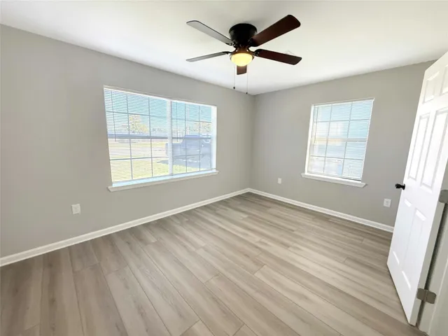 an empty room with wooden floor and windows